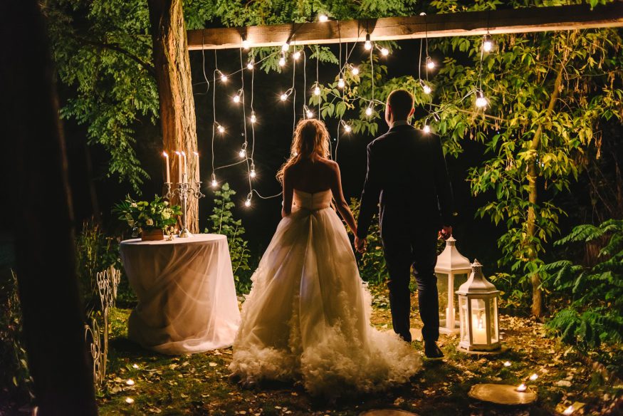 A bride and groom stand at a rustic alter in the woods