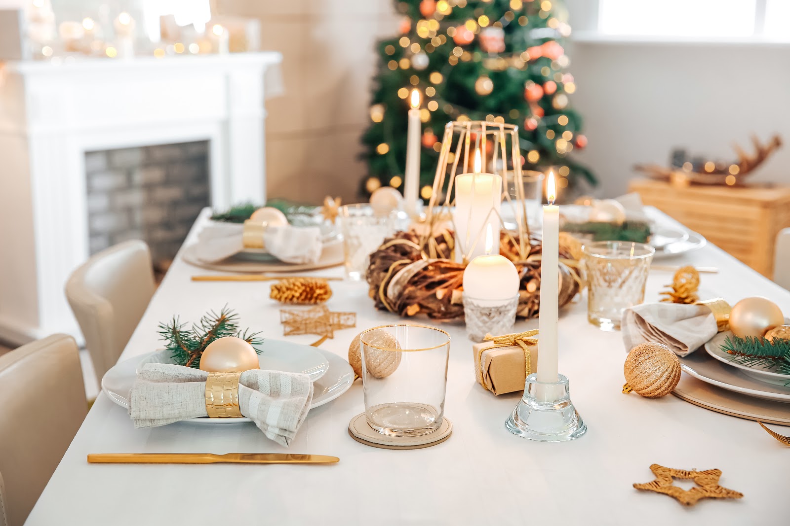 Christmas decorating ideas: A table with white and gold place settings and a Christmas tree in the background