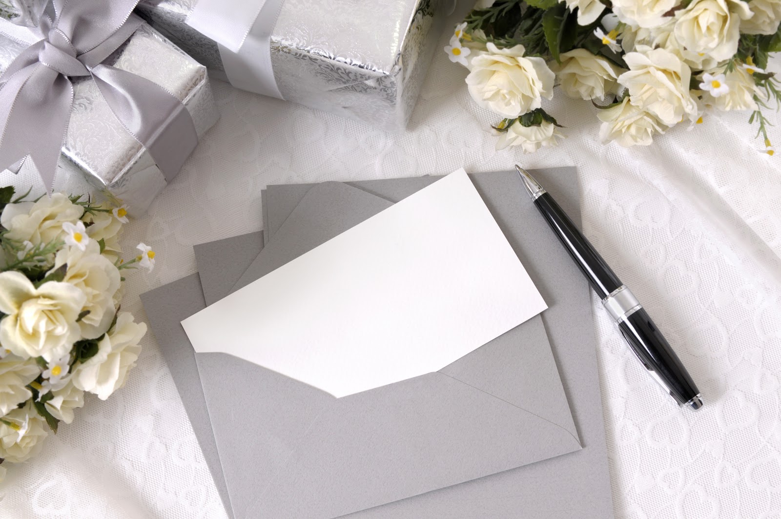 Wedding wishes: Wedding gifts, flowers, and a blank note and pen next to an envelope