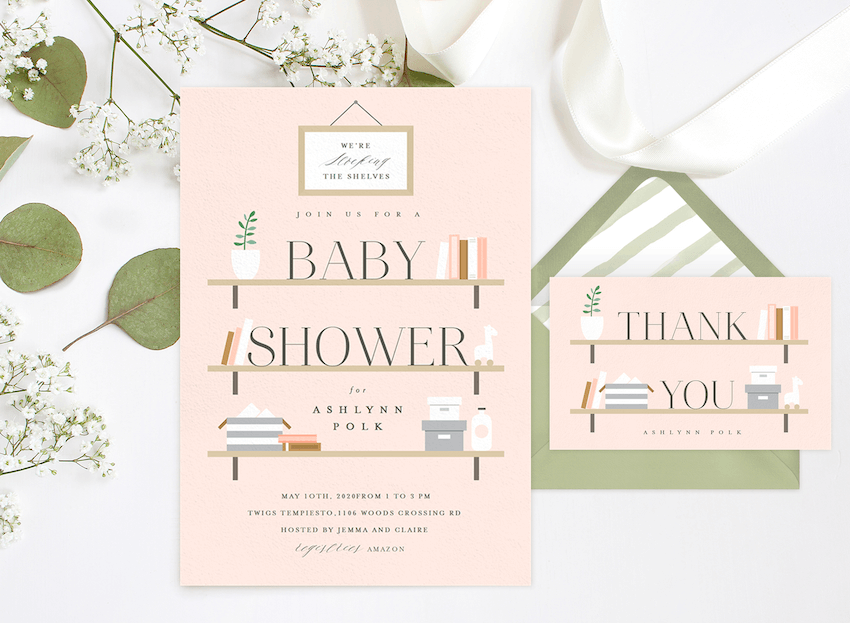 A baby shower invite next to a matching thank you card, surrounded by ribbon and baby's breath