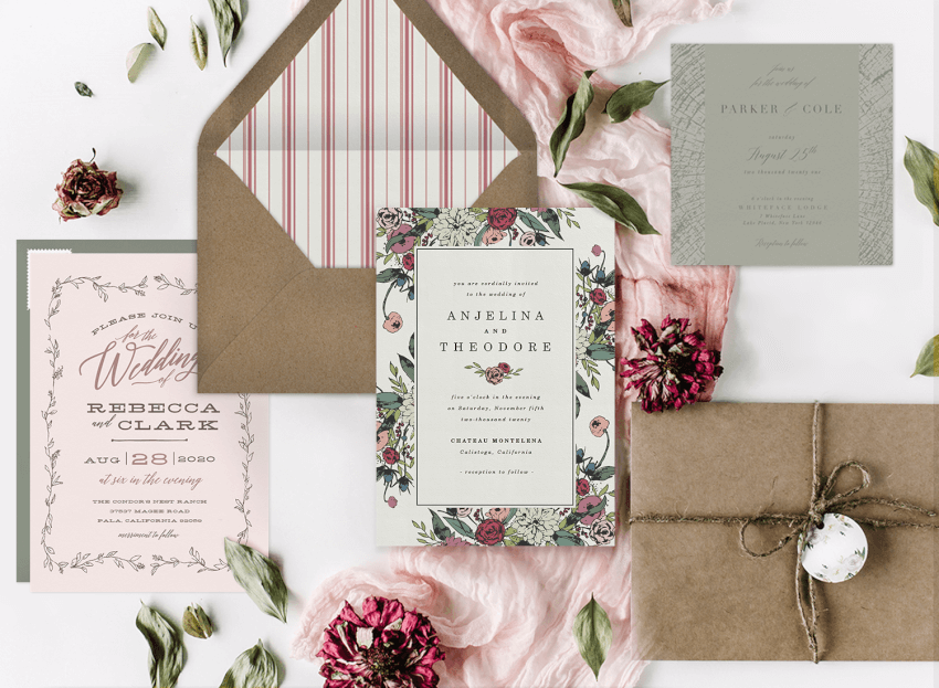 Rustic wedding invitations laid out with their envelopes and flowers
