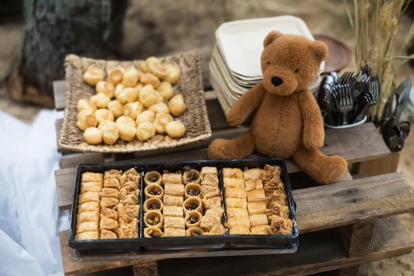 One happy camper birthday: appitizers, plates, and a teddy bear on a table