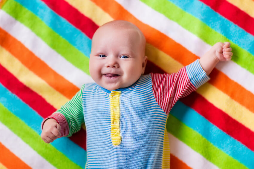 Rainbow baby shower: baby lying on a rainbow blanket