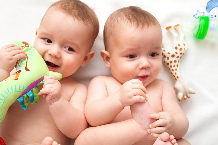 Twin baby shower ideas: baby twins lying on a bed
