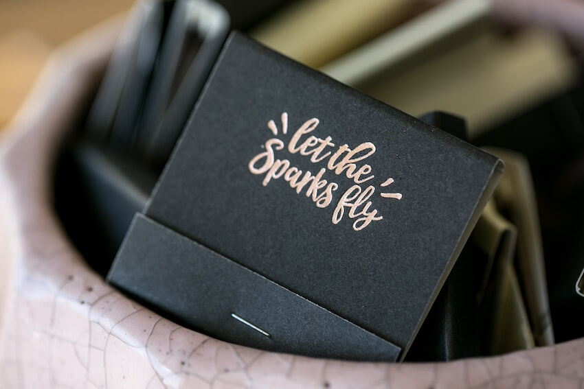 Black matchbook with the words "let the sparks fly" on it
