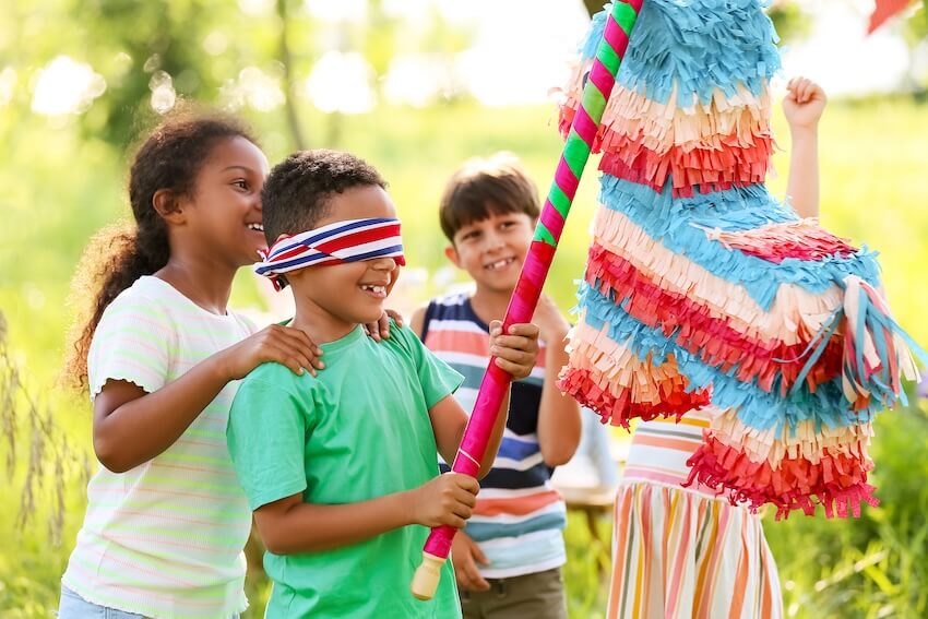 5th birthday party ideas boy: blindfolded boy trying to hit a piñata