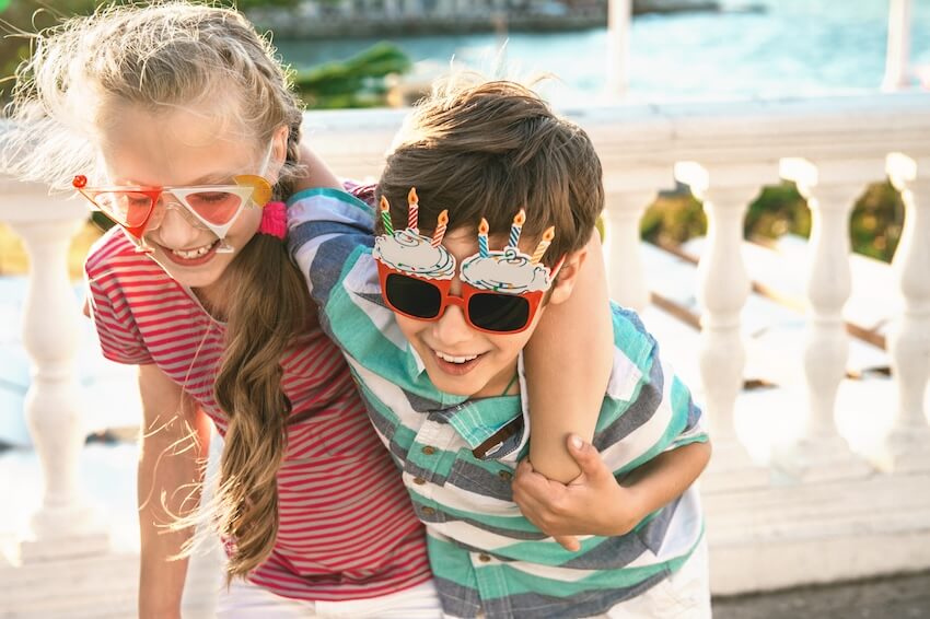 Summer birthday party themes: boy and girl wearing funny party glasses
