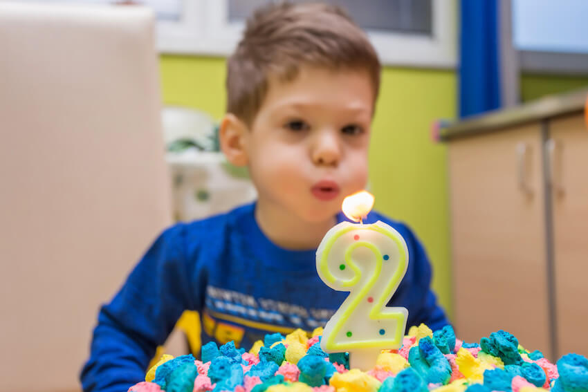 Two wild birthday: boy blowing out a candle on a birthday cake