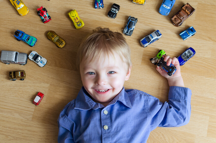 Boy lying on the floor with his toy cars