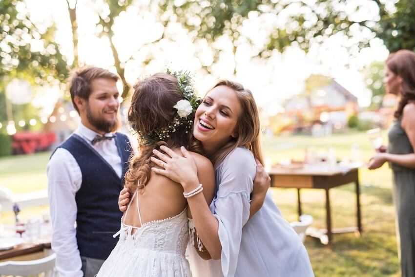 Wedding guest etiquette: bride hugging a woman