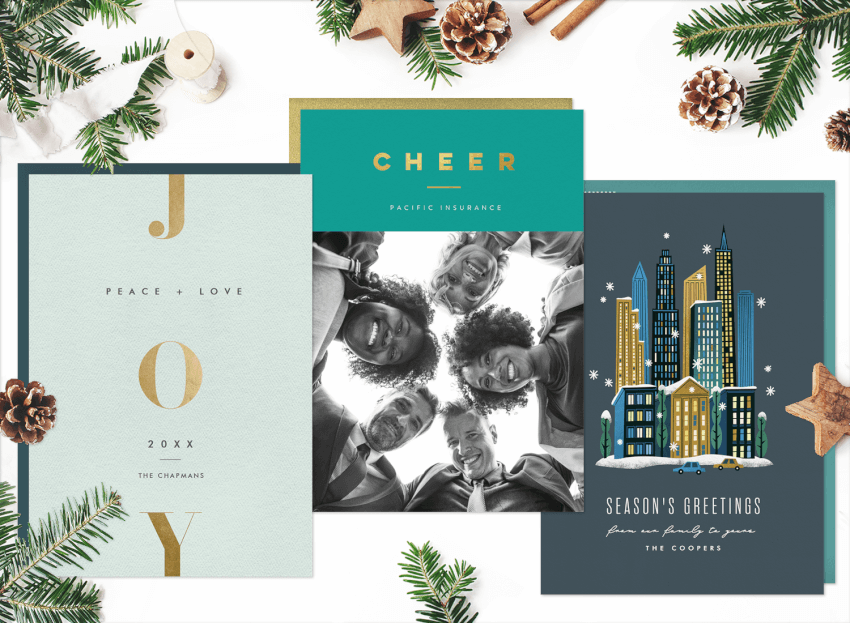 Three different designs for business Christmas cards, surrounded by pinecones and greenery 