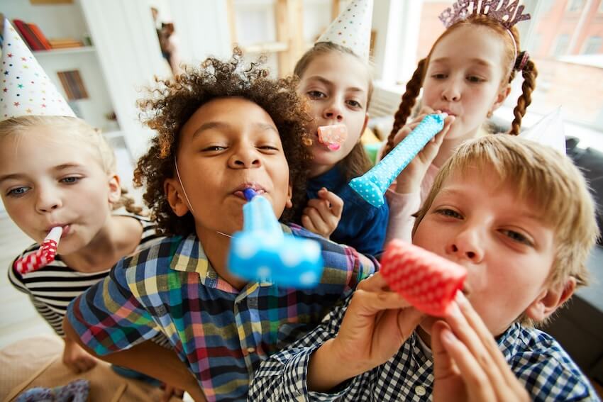 Birthday wishes for kids: close up of 5 kids blowing party horns