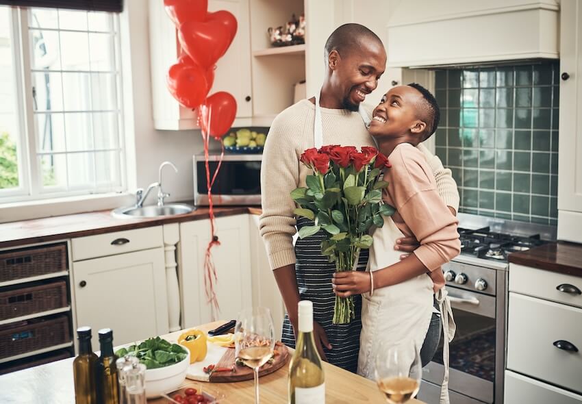 Traditional wedding gifts: couple happily looking at each other while holding a bouquet of roses