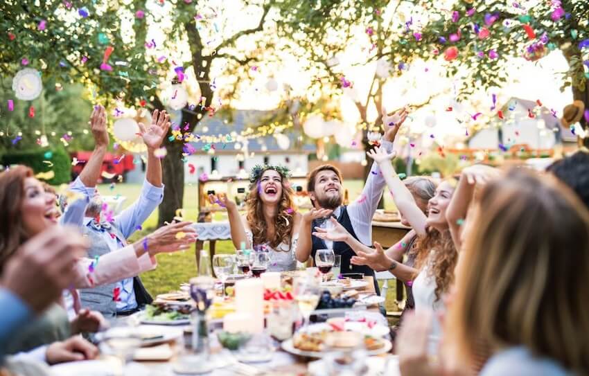 Family and friends throwing confetti at an outdoor reception