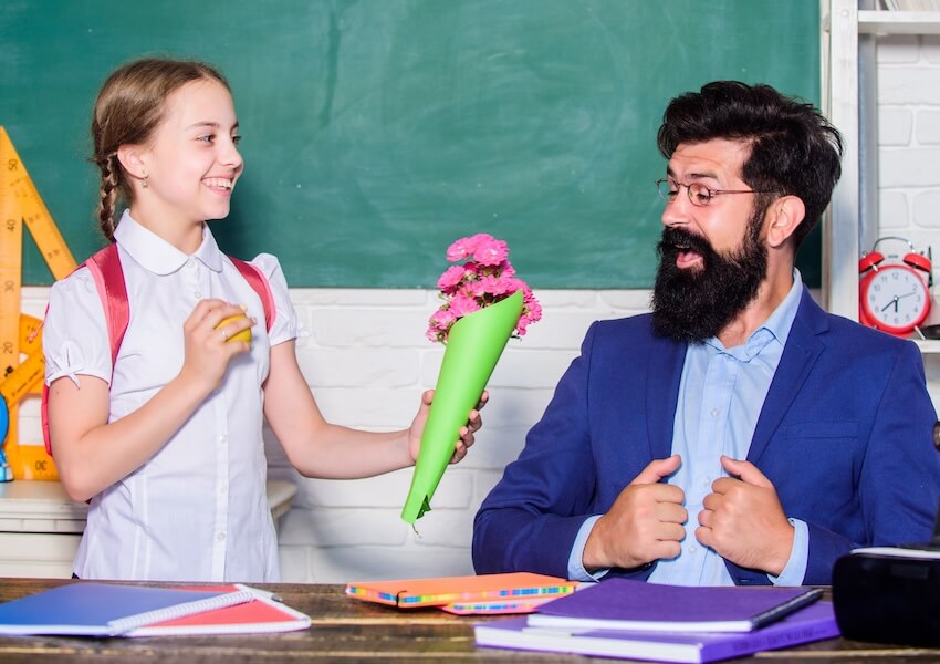 Girl giving a bouquet of flowers to her teacher