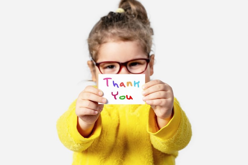 Young girl holding up a thank you card