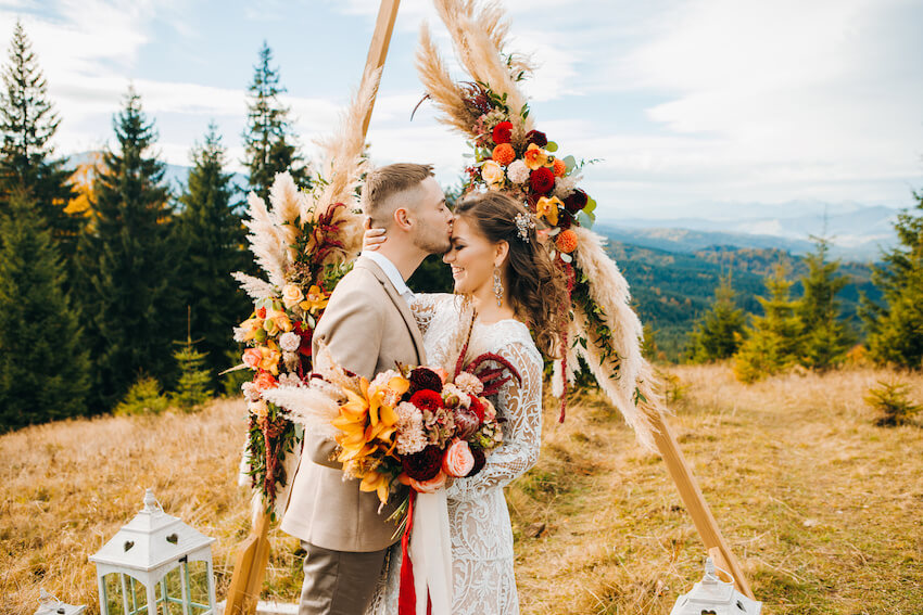 Outdoor wedding decorations: groom kissing his bride on the forehead