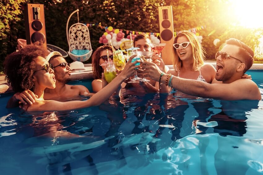 Group of friends clicking their glasses while in a swimming pool
