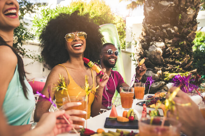 Group of friends happily eating and drinking outdoors