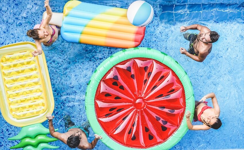 Pool party invitations: group of friends in pool with colorful floaties