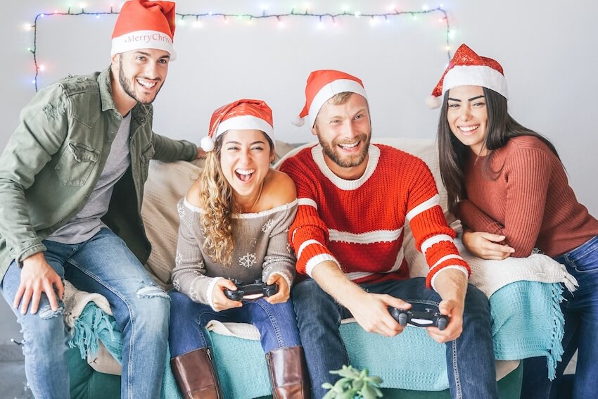 Holiday party games: group of friends wearing Santa hats, playing a video game