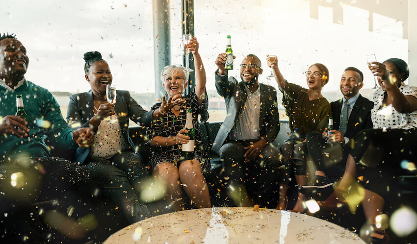 Group of people happily toasting while confetti falls from above