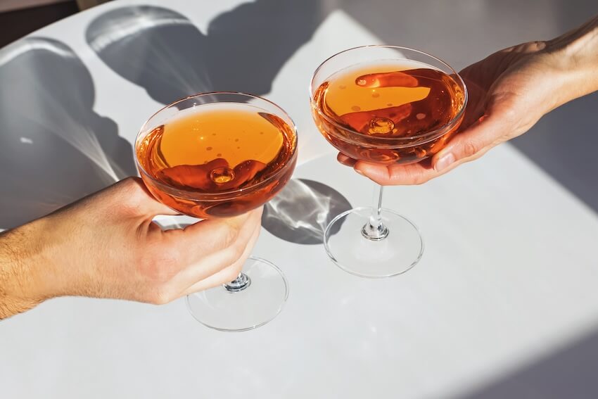 Party favors for adults: hands holding coupe glasses with cocktails