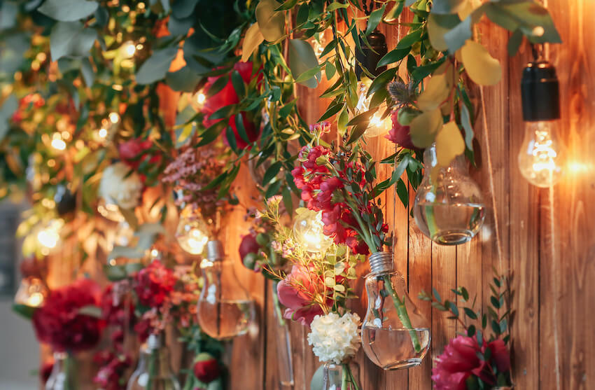 Outdoor wedding decorations: lights and flowers on a wall