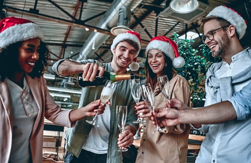 Work holiday party: man pouring champagne into his friends' champagne glasses