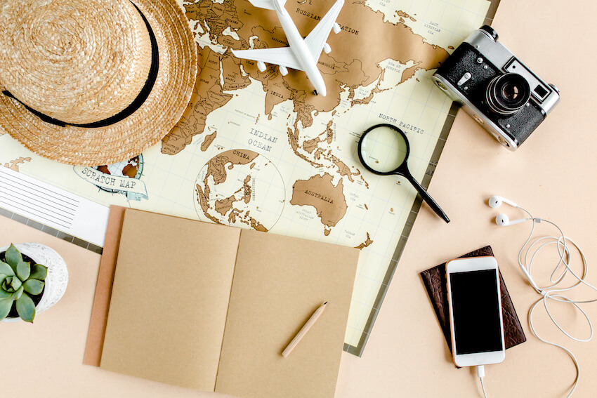 Farewell party: map, notebook, phone, camera, hat, and a toy airplane