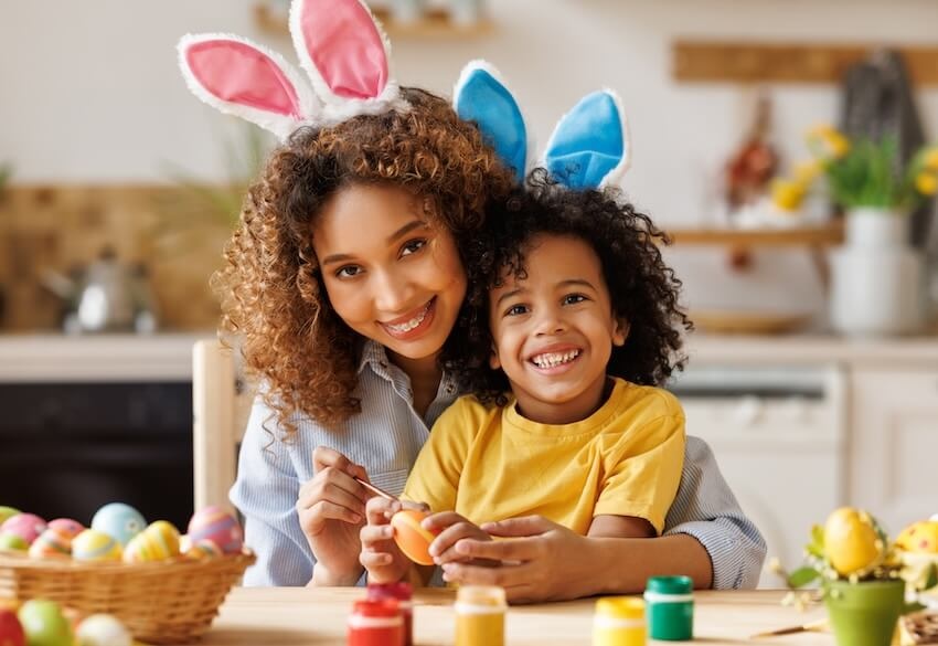 Mother and her child wearing bunny ear headbands while smiling at the camera