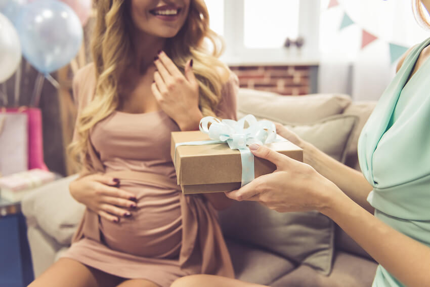 Gender neutral baby shower: person giving a gift to a pregnant woman