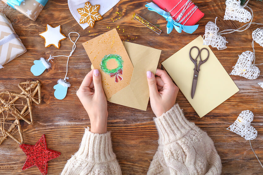 Watercolor Christmas cards: person putting a Christmas card inside an envelope