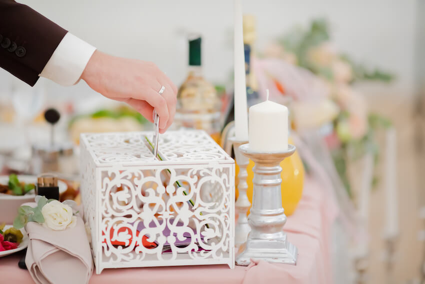 Cute ways to ask for money as a wedding gift: person putting a card inside a box