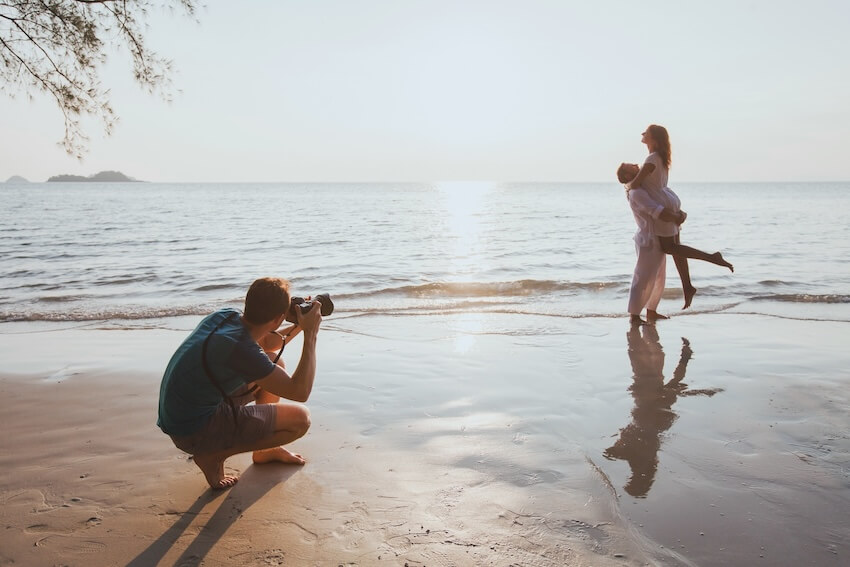 Save the date photo ideas: photographer taking a photo of a couple at the beach