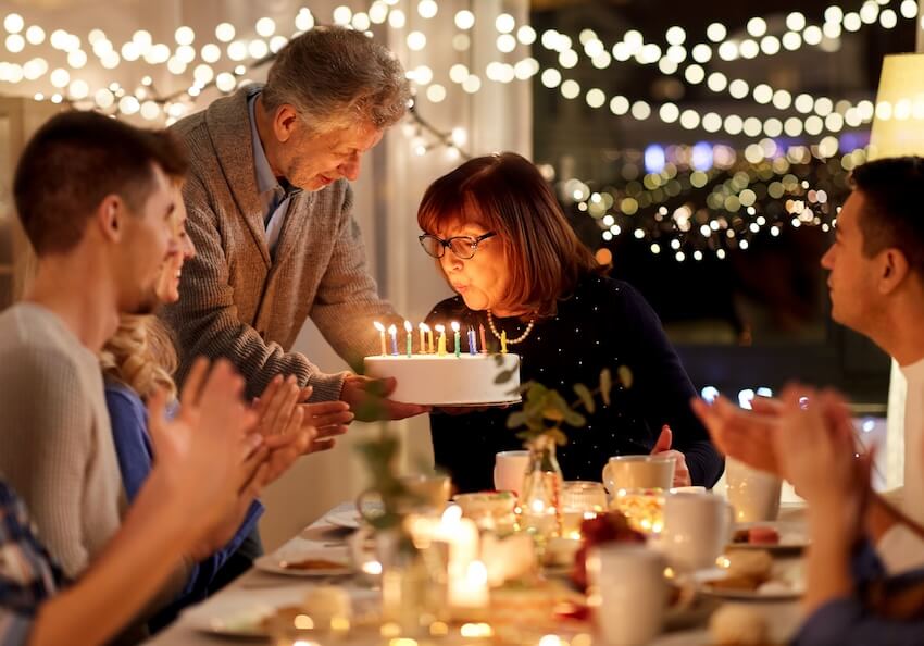 Spiritual happy birthday blessings: senior woman blowing out candles on her birthday cake