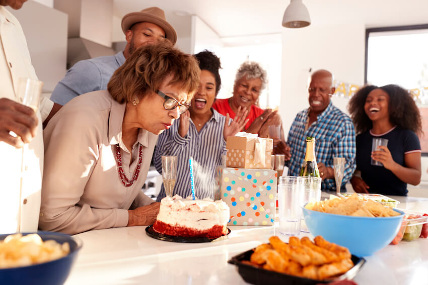75th birthday decorations: senior woman blowing out her birthday candle