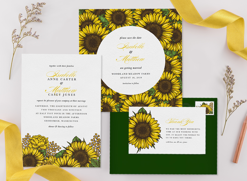 Three sunflower wedding invitations with an envelope, ribbon, and flower sprigs