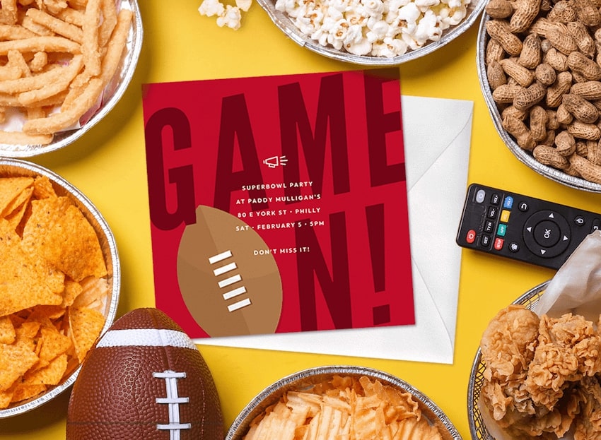 Super Bowl party invitations surrounded by various snacks