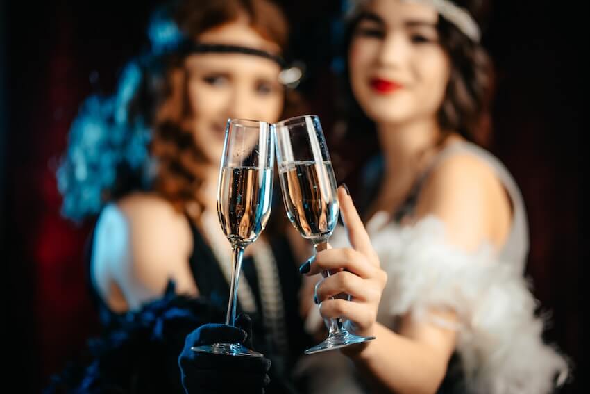 Murder mystery party ideas: two women clinking their champagne glasses