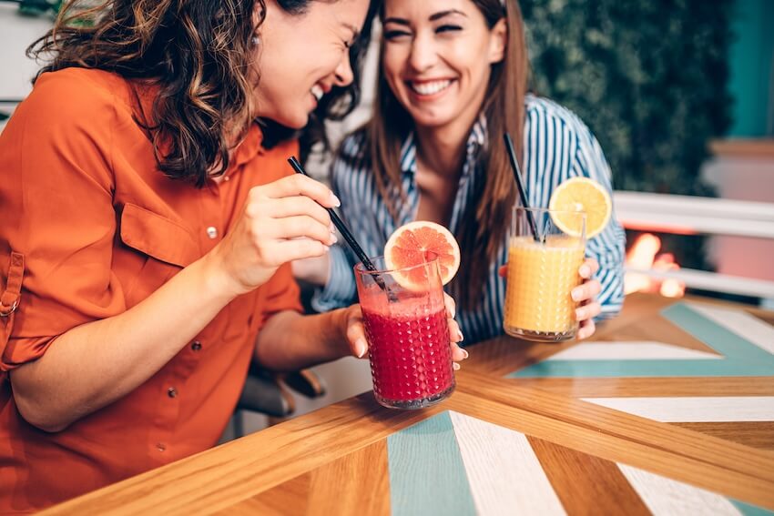 Two women laughing while enjoying their smoothies