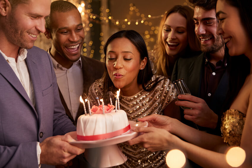 Golden birthday: woman blowing out candles on her birthday cake