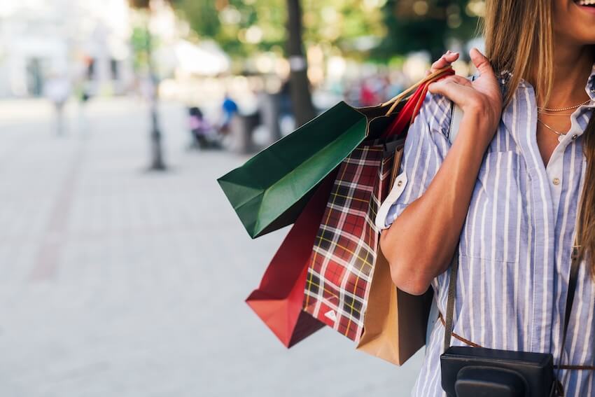 Woman carrying 4 paper bags while walking