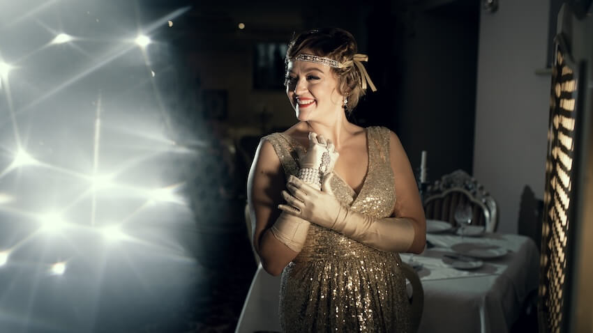 Woman happily wearing a golden dress and a pair of opera gloves