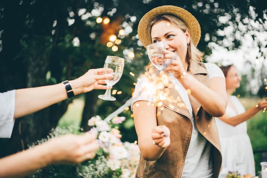 Summer bridal shower themes: woman holding a sparkler while raising her glass