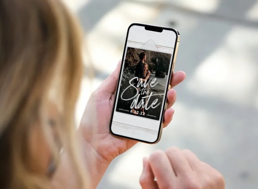Woman looking at a digital save the date text on her phone