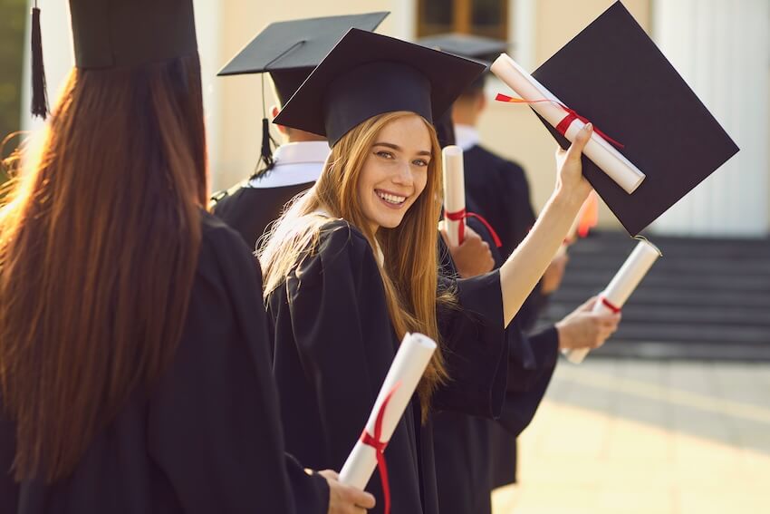 Graduation gifts for her: woman showing her diploma while smiling at the camera